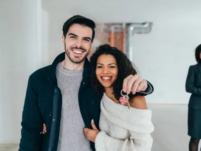 Lachend koppel met de sleutel van hun nieuwe woning Lachend koppel met de sleutel van hun nieuwe woning