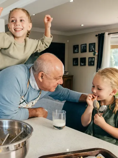 Opa die met zijn twee kleindochters in de keuken staat Opa die met zijn twee kleindochters in de keuken staat