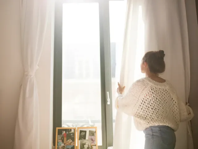Vrouw aan het gordijn